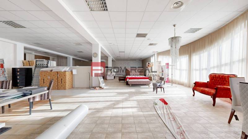 Interior of a building with furniture, a red sofa, a bed, and tables with documents.