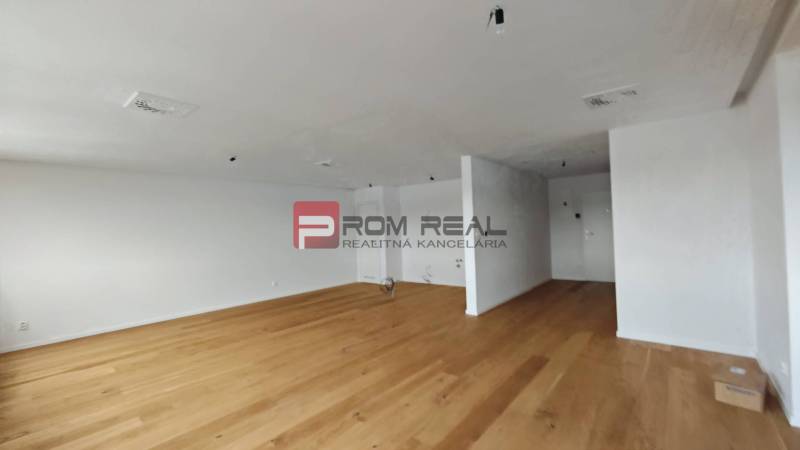 A spacious room with wooden flooring in a 4-room apartment, light walls, and simple furnishings.