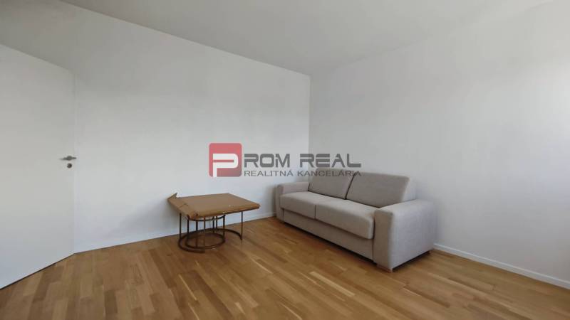 A room in a 4-room apartment with a sofa and a table on a wooden floor.