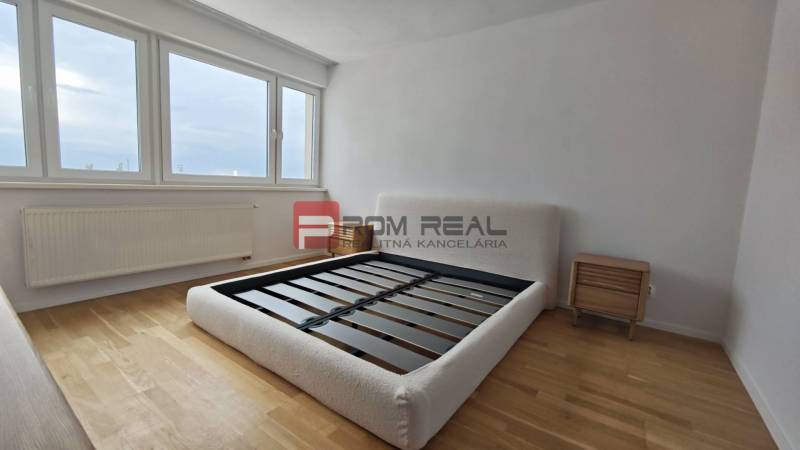 A bright bedroom with wooden flooring and a bed in a 4-room apartment.