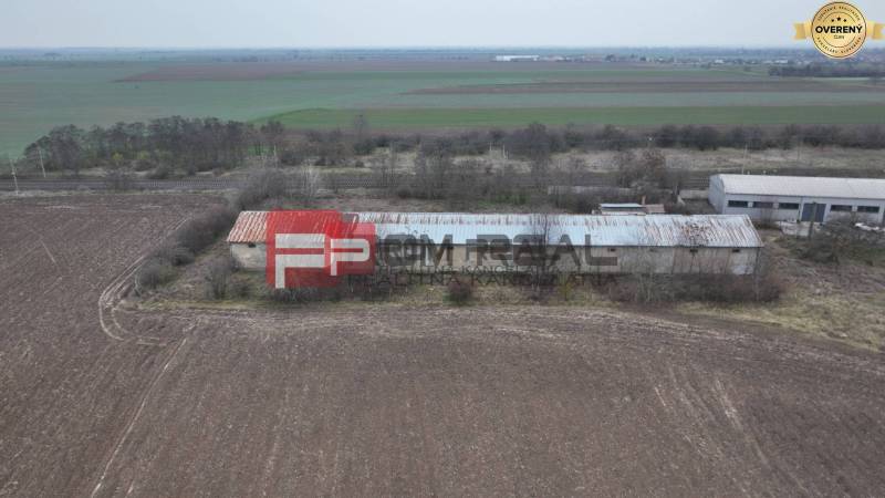The building on Partizánska Street, surrounded by fields, warehouses, and halls in the background.