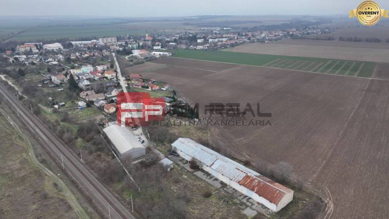 Aerial view: on Partizánska Street, there are fields, warehouses, and halls near the tracks.