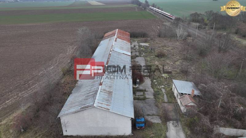 The image shows warehouses and halls on Partizánska Street, surrounded by fields and a railway.