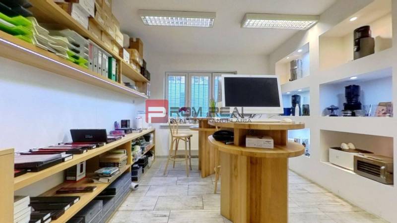 Commercial space with shelves full of documents, devices, and a computer on the desk.