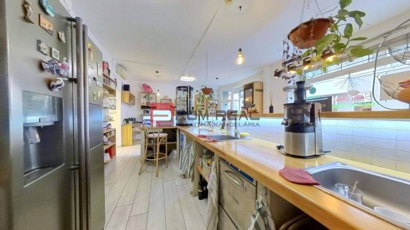 A kitchen in commercial premises with wooden furniture, appliances, and hanging plants.