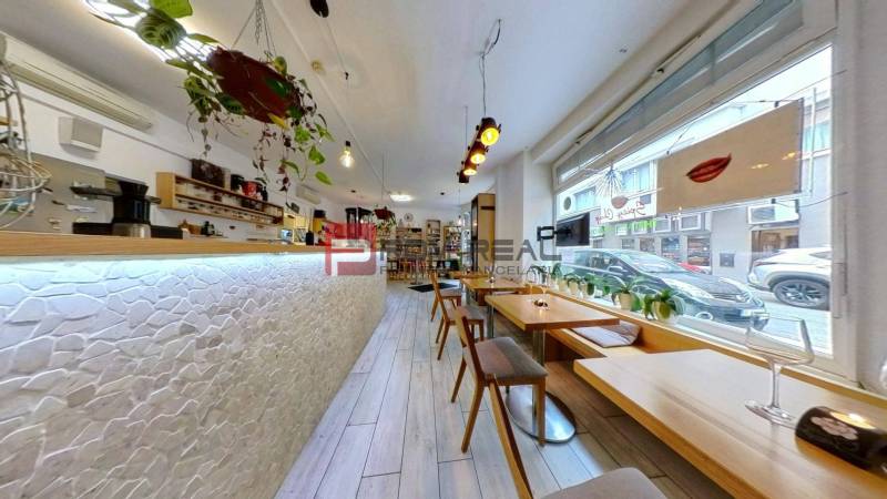 A café with wooden tables and a bar counter, commercial spaces with plants.