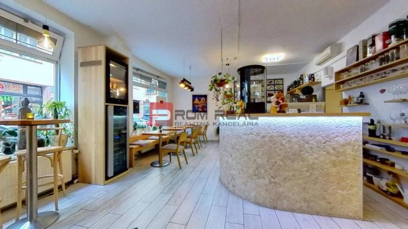 Café with chairs and tables, light wooden floor, decorations, and a bar counter.