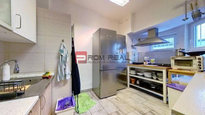 A kitchen in commercial premises with appliances, shelves, and tiles.