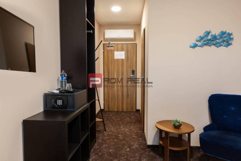 A hotel room with furniture, a safe, and a television, decorations on the wall.