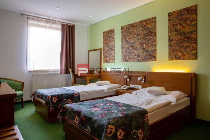 A hotel room with two beds, paintings of a lion, and wooden furniture.