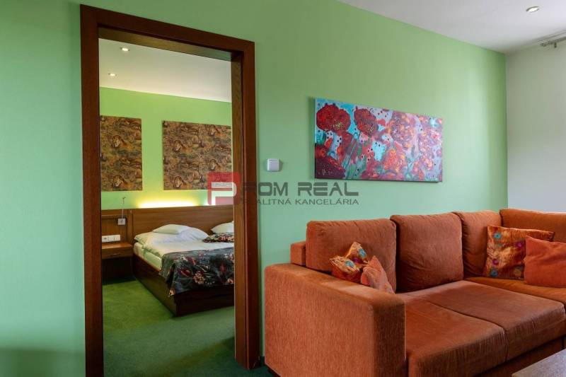 Interior of a guesthouse with an orange sofa, paintings, and a bed with colorful covers.