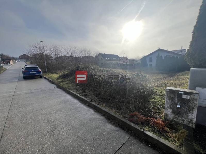 Land for residential use in Stupava on Bazova Street, sunny environment and a car by the road.