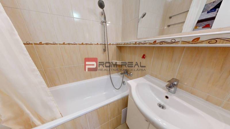 A bathroom in a 3-room apartment with a bathtub and a shower, tiled with beige tiles.