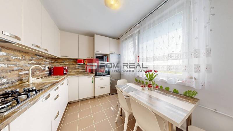 A kitchen in a 3-room apartment with flowers on the table and appliances.