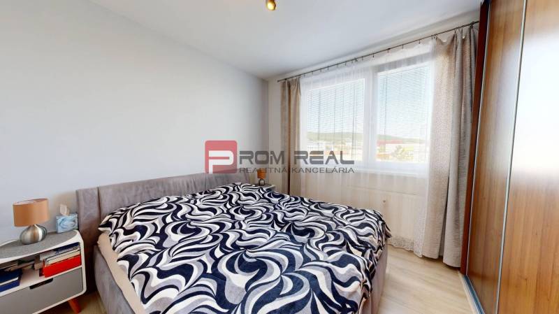 Bedroom in a 3-room apartment with a large window, bed, cabinet, and decorative throw.