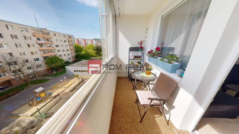 The balcony of a 3-room apartment with a view of the children's playground and residential buildings.