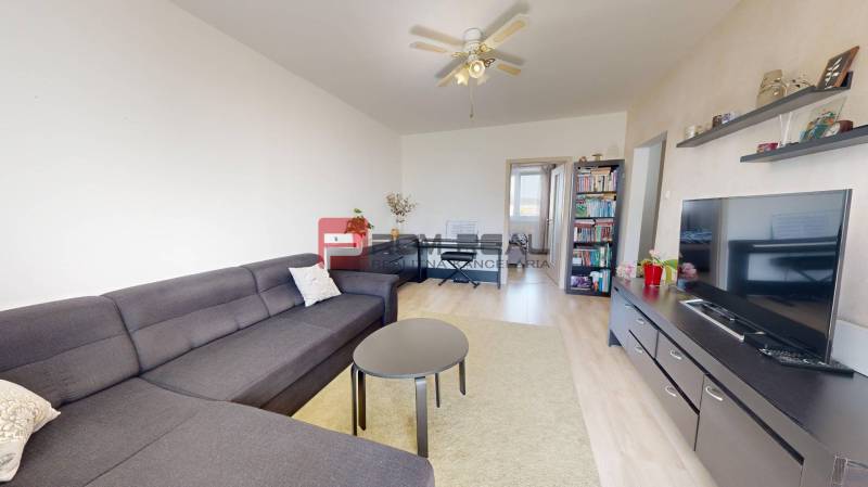 Living room in a 3-room apartment with a gray sofa, coffee table, and television.