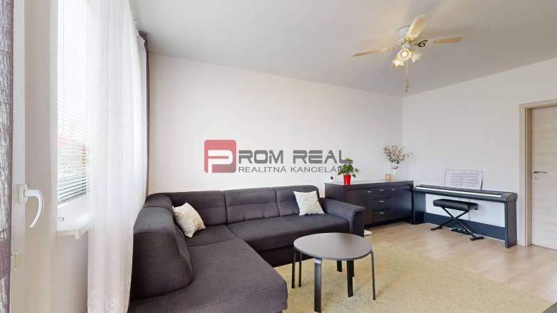 Living room in a 3-room apartment with a corner sofa, a coffee table, and a piano.