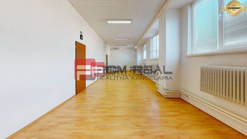 A spacious bright room with wooden flooring, radiators, and windows in warehouses and halls.