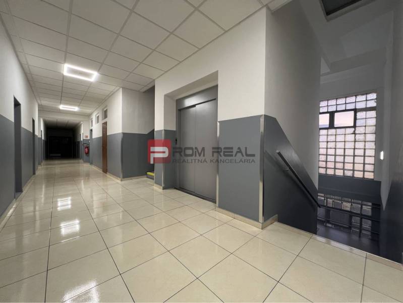 A corridor with a staircase, an elevator, and a tiled floor in warehouses and halls.