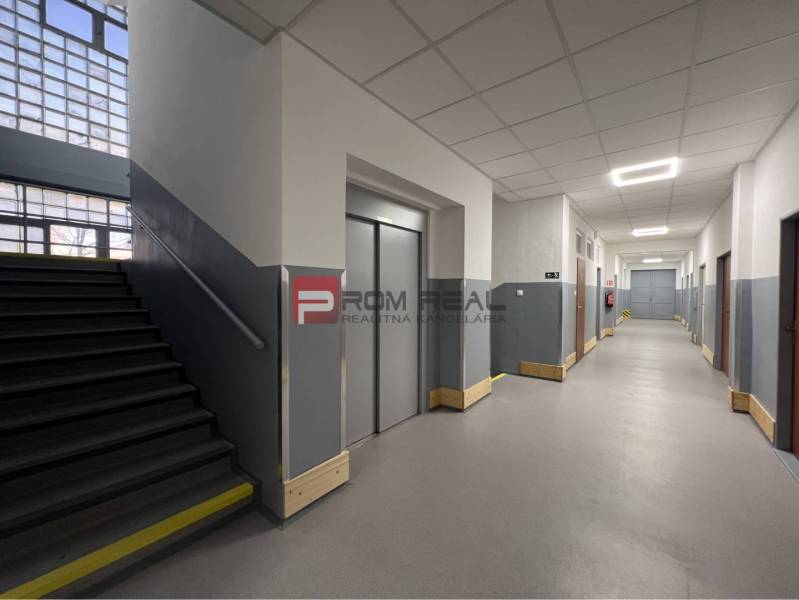 Interior of a warehouse and hall with stairs and an elevator, gray walls, bright corridor.
