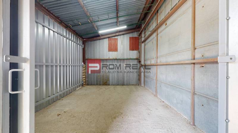 A metal storage room with open doors in an industrial hall.