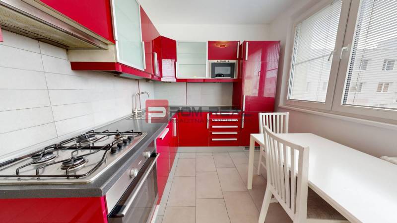 A kitchen with red cabinets, a gas stove, and a white dining table in a four-room apartment.