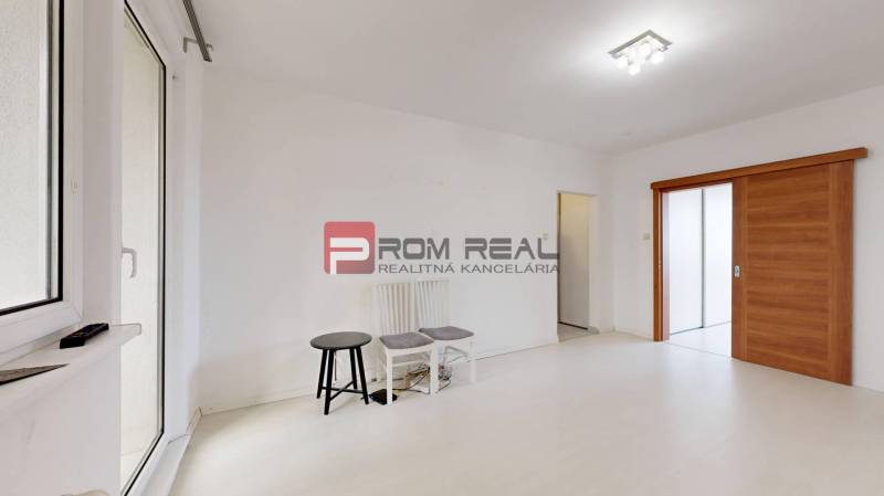 A bright room with white walls, sliding wooden doors, and two chairs in a 4-room apartment.