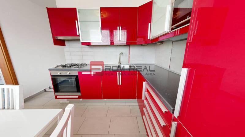 A red kitchen in a 4-room apartment with a gas stove and a white table.