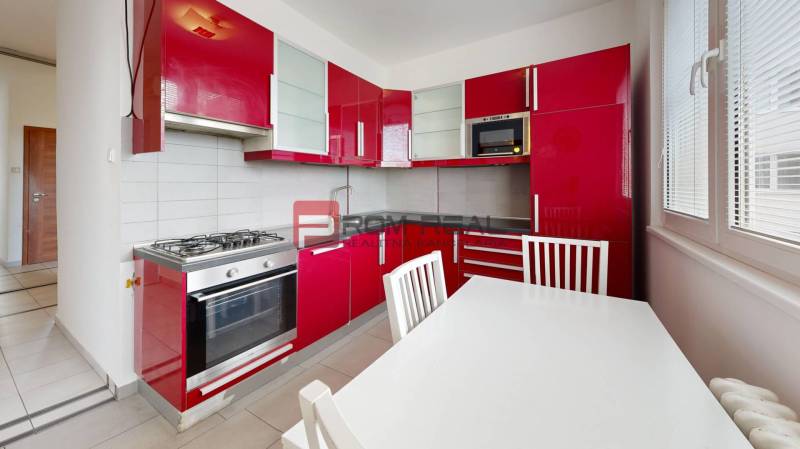 A kitchen with red cabinets and a gas stove in a 4-room apartment.
