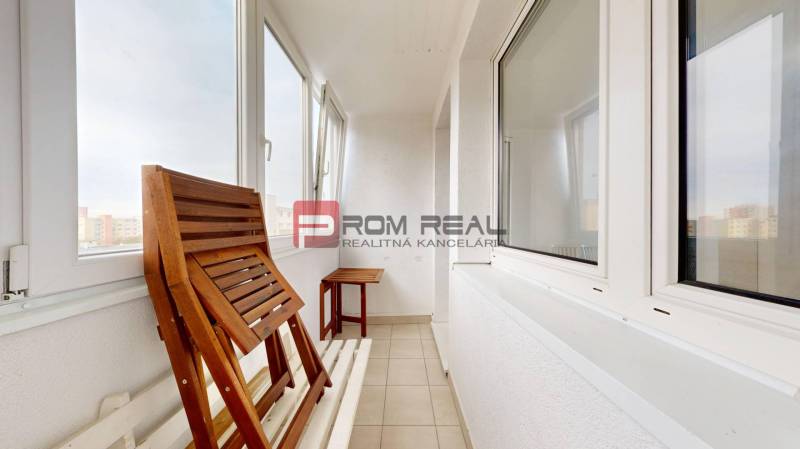 Glazed balcony of a 4-room apartment with wooden furniture and a view of the city.