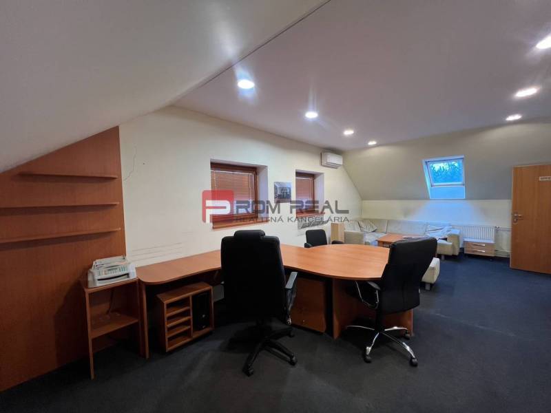 Office manufacturing space with chairs and a table, illuminated by artificial light.