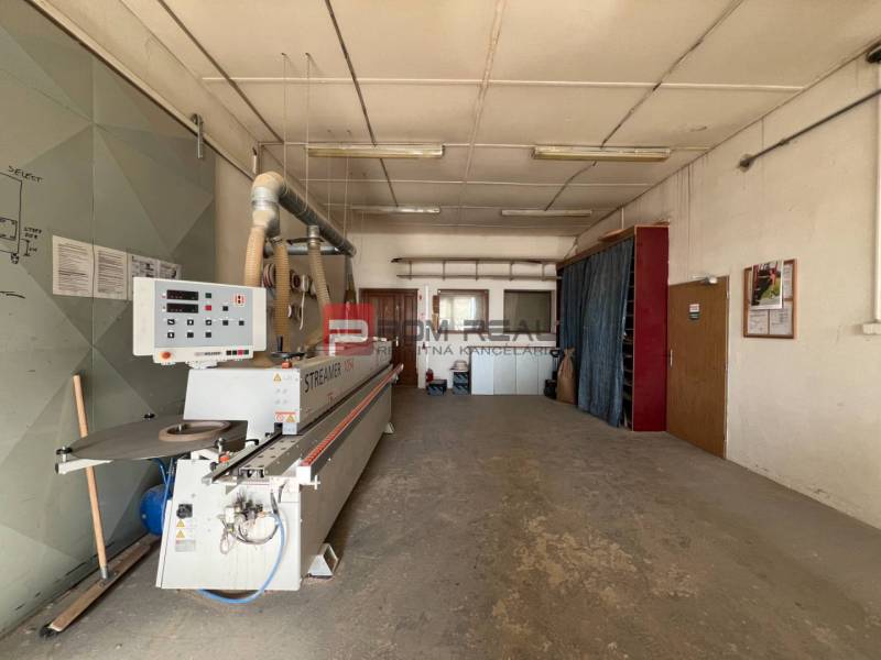 Manufacturing premises with a large machine and pipes on the ceiling.