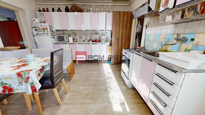 A kitchen in a family house with white and pink cabinets, a dining table, and a stove.