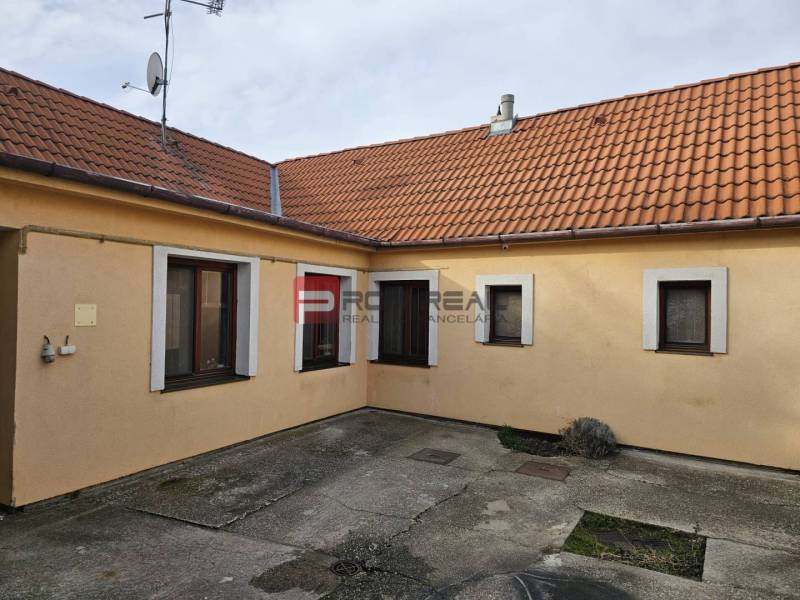 The yard of a family house on Slnečná Street in Pezinok with concrete paving and an orange facade.