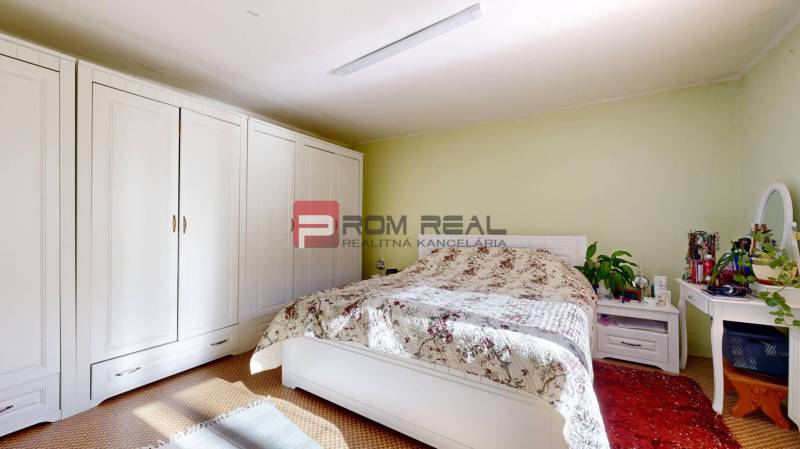 Bedroom with a large wardrobe, bed with a floral bedspread in a family house.