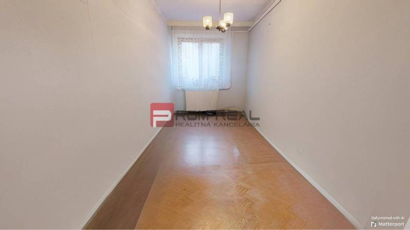 A narrow room with a wooden floor and a centrally located window under a chandelier. Family house.