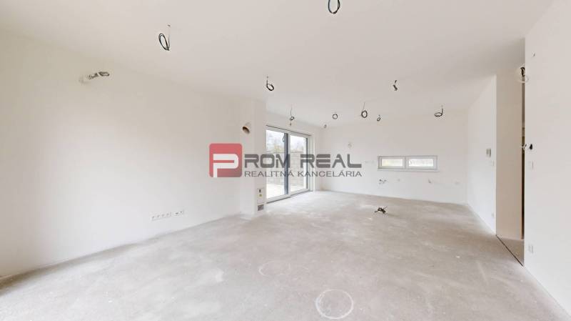 A spacious unfurnished room in a family house with white walls and a large window.