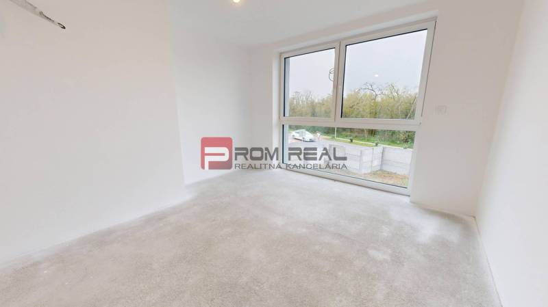 A bright, empty room in a family house with a large window and a view of the garden.