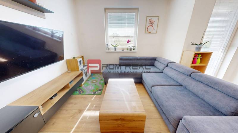 Living room in a 3-room apartment with a corner sofa, TV, and wooden furniture.