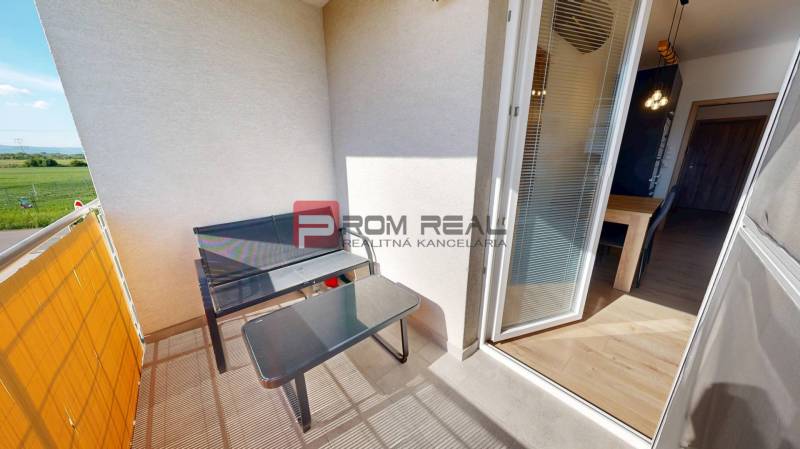 The balcony of a 3-room apartment in Tomášov, Pri Kaštieli, with an outdoor table and chairs.