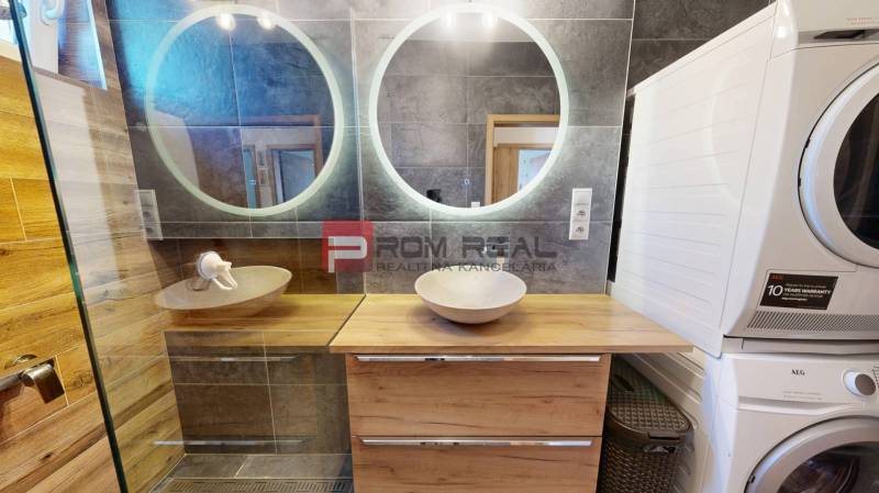 A bathroom in a 3-room apartment with a double sink and a washer with a dryer.