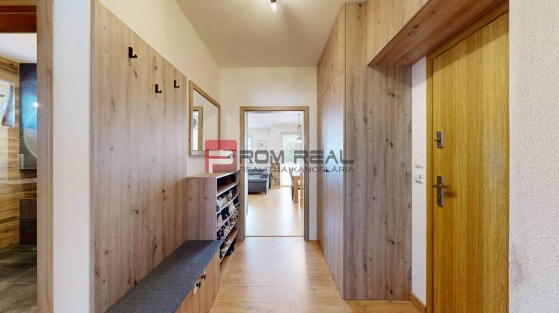 Interior of a 3-room apartment with a wooden hallway, a wardrobe, and a mirror on the wall.