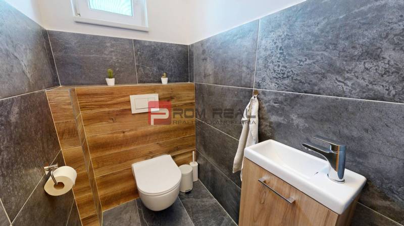 A bathroom with wood and stone tiles in a 3-room apartment, with a small sink.