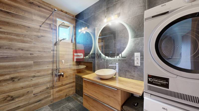A bathroom in a 3-room apartment with wooden paneling, a sink, and an AEG washing machine.