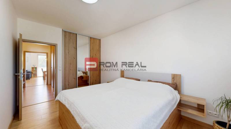 Bedroom in a 3-room apartment with wooden floors and a bed with a white throw.