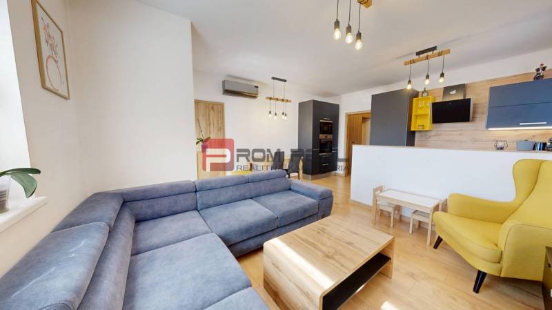 Living room of a three-room apartment with a blue sofa, wooden furniture, and a yellow armchair.