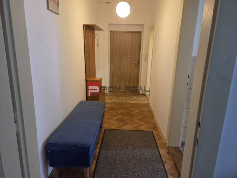 A hallway with a blue bench and wooden doors, furnishing a 2-room apartment.