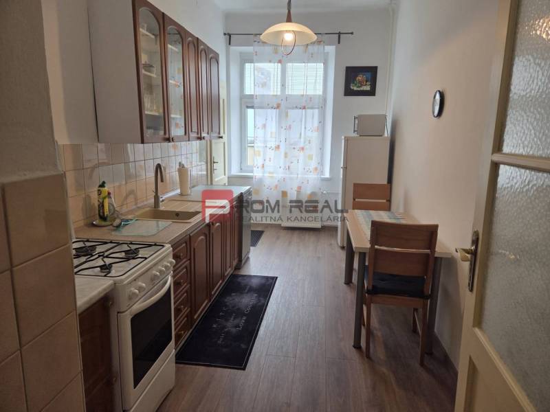Kitchen in a 2-room apartment with a gas stove, dining table, and cabinets.