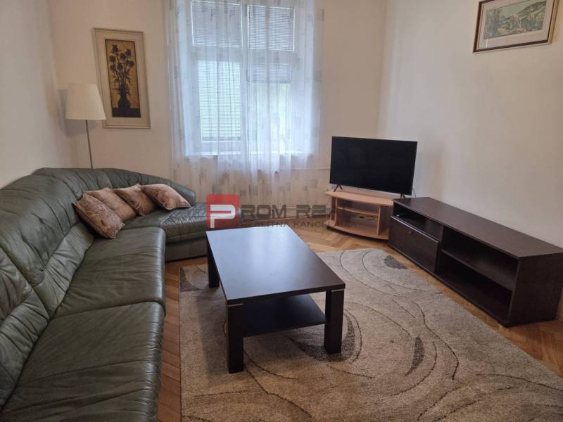 Living room with a corner sofa, television, and coffee table in a two-room apartment.